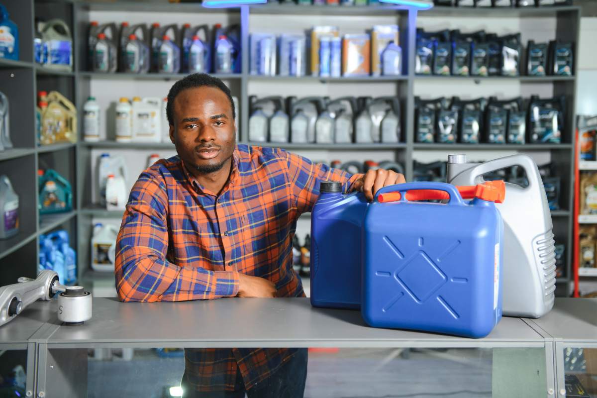 seller man with canister of motor oil in auto store.