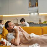 Man with running nose lying with used tissues in bed