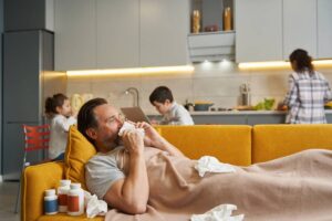 Man with running nose lying with used tissues in bed