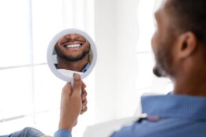 Black guy patient of dental clinic looking at mirror