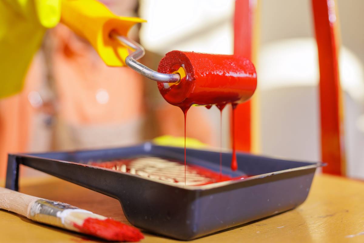 fire retardant paint Close macro of red paint roller over tray with drips in a home DIY furniture renovation scene with copy space
