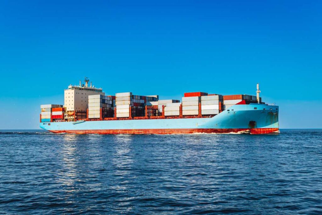 A massive cargo vessel navigating the open ocean on a bright sunny day